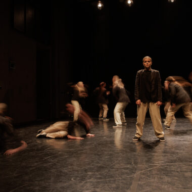 Spektakl tańca współczesnego. Na scenie grupa tancerek i tancerzy w dynamicznych pozach.